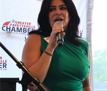 Female with brown hair speaking into microphone at an event